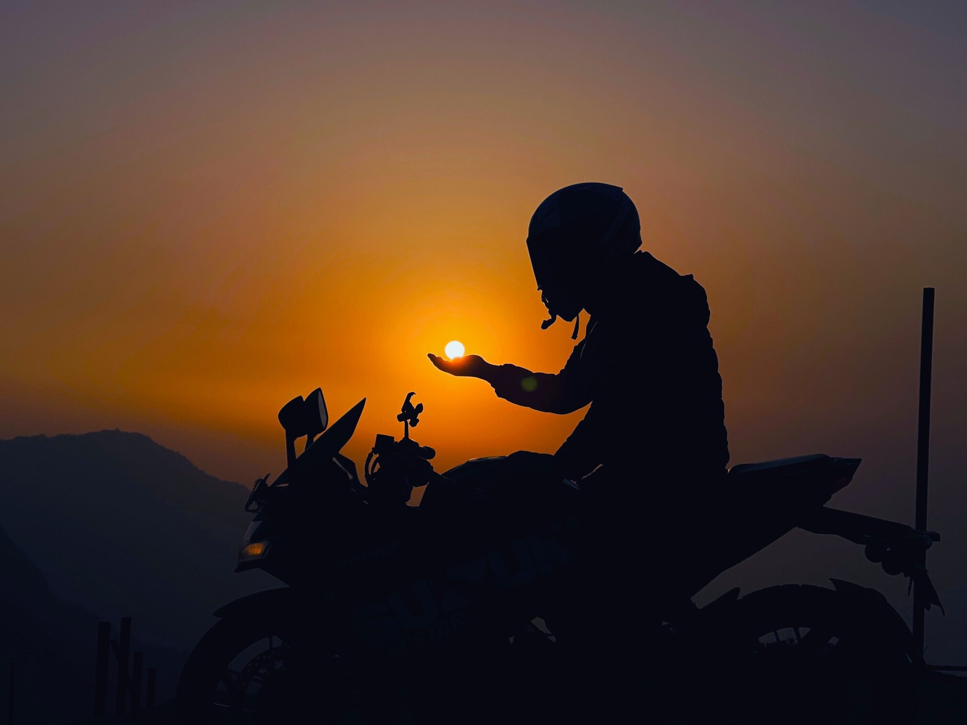 Rider and motorcycle silhouetted against a golden sunset